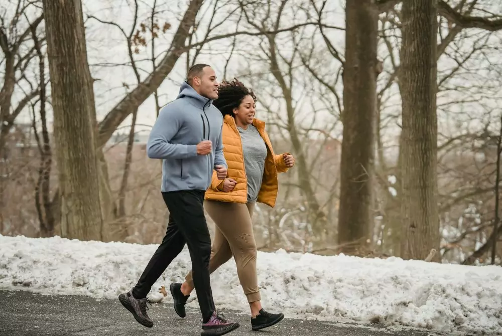Two people running on a path in winter with snow