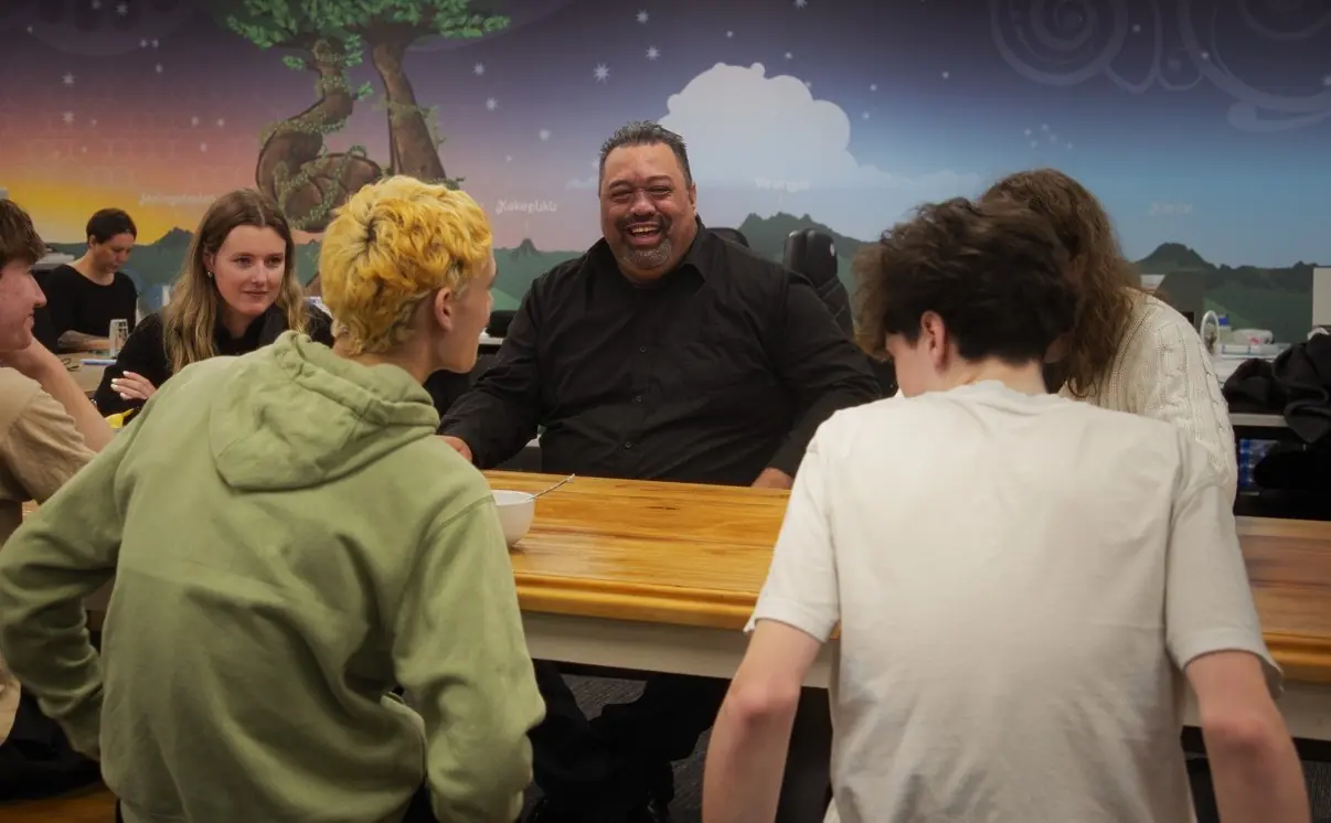 A group are sitting around a table chatting.